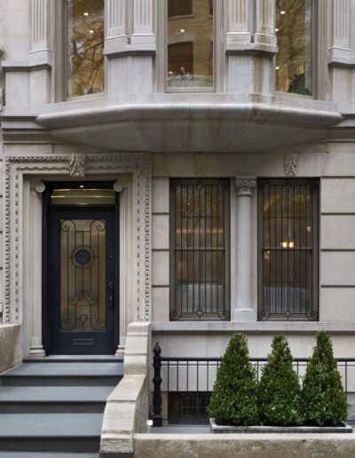 Elegant urban entryway with wrought-iron door and symmetrical shrubbery.