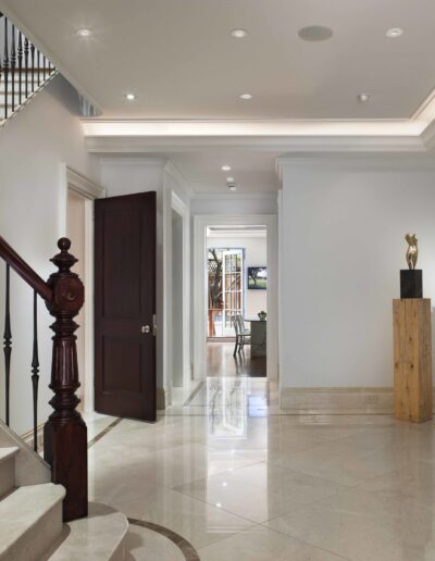 Elegant interior hallway with a marble floor, staircase, and tasteful furnishings.