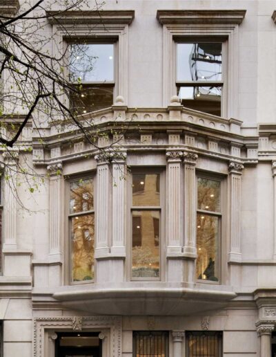 Facade of a classic stone building with large windows and ornate architectural details.