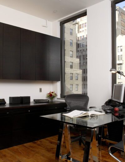 Modern home office with a black desk, ergonomic chair, and city view.