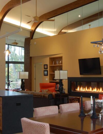 Modern open-plan living space with a kitchen and dining area leading to a cozy sitting area with a fireplace.