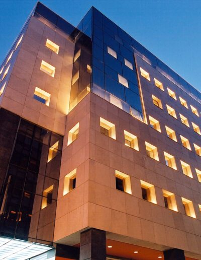 Modern office building at dusk with illuminated windows.