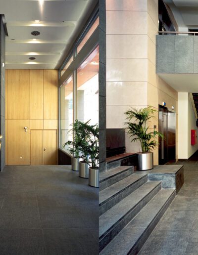 Modern office lobby with a reception desk and staircase.