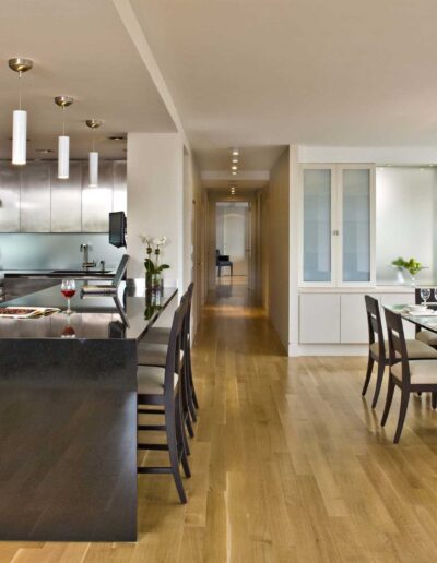 Modern kitchen and dining area with stainless steel appliances, a central island, and a wooden dining table set under pendant lighting.