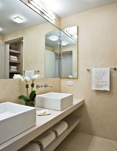 Modern bathroom interior with double sinks, mirror, and separate toilet area.