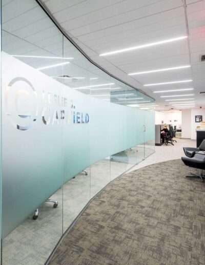 Modern office corridor with frosted glass partitions and an exit sign.