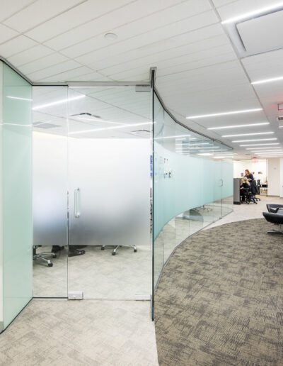 Modern office interior with glass partitions and a curved pathway.