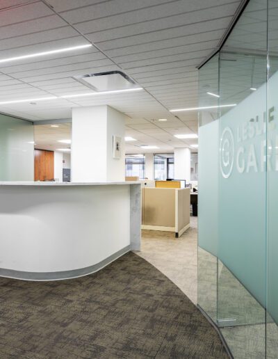 Modern office reception area with glass walls and company logo signage.