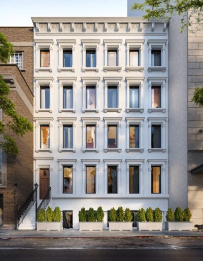 A renovated classic townhouse with a white façade and decorative trim, situated between older buildings on an urban street.